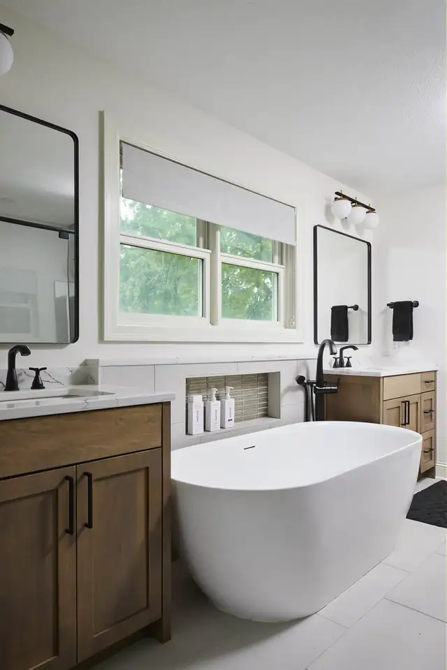 Owners' suite bathroom in St. Louis Park, Minnesota with a freestanding tub, maple vanity and white quartz countertop