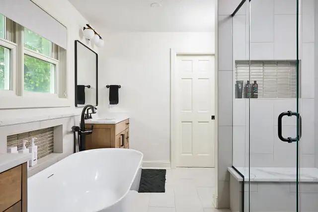 Owners' suite bathroom remodel in St. Louis Park, Minnesota with a freestanding tub, glass shower and maple vanity with white quartz top