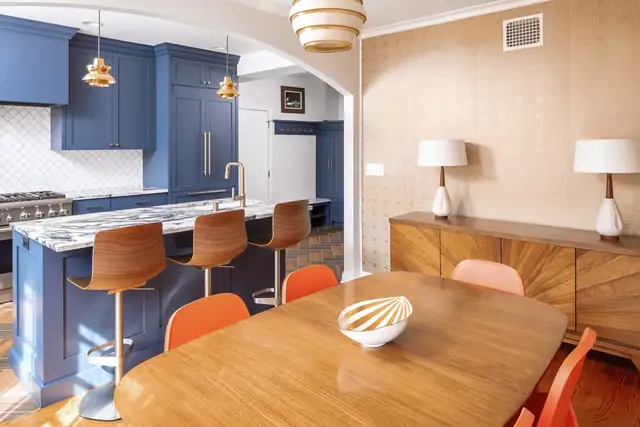 Minneapolis kitchen remodel with navy blue cabinets, a marble-look island, wood stools and concrete herringbone tile flooring