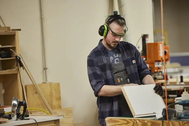 Sicora cabinet shop craftsman in ear protection checking a cabinet door
