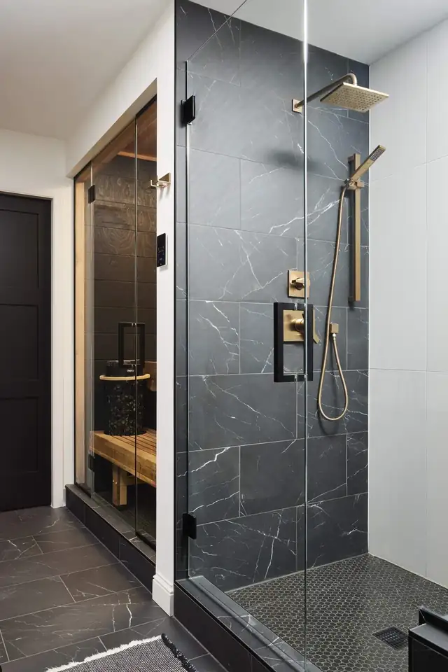 Walk-in shower with charcoal marble-look tile, brushed brass fixtures and frameless glass